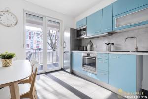 eine Küche mit blauen Schränken, einem Tisch und einem Fenster in der Unterkunft Pineapple Apartments Dresden Zwinger IV - 65 qm - 1x free parking in Dresden