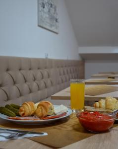 una tavola con piatti di cibo e un bicchiere di succo d'arancia di Apartments Ozren a Soko Banja