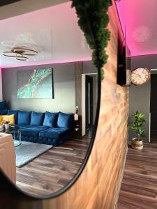 a mirror reflecting a living room with a blue couch at Apartamente A&A in Tîrgu Ocna