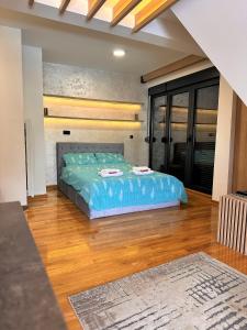 a bedroom with a blue bed in a room with wooden floors at Lexi Bombonjera apartman in Divčibare