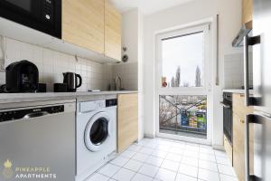 a kitchen with a washing machine and a window at Pineapple Apartments Dresden Mitte III - free parking in Dresden