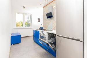 a kitchen with blue cabinets and a refrigerator at TOTU HOME Seaside Sopot Helska Apartment in Sopot