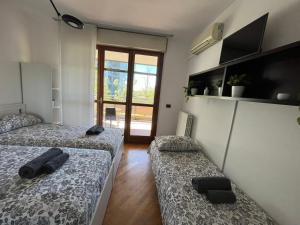 Zimmer mit 2 Betten und einer Tür zu einer Terrasse in der Unterkunft BedandBreakfast Eni Torri Lombarde San Donato BBqueen in San Donato Milanese