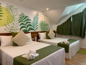 two beds in a room with green and white wallpaper at ROYAL SUITES - PORT BARTON in San Vicente