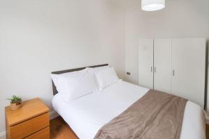 1 dormitorio con cama blanca y tocador de madera en Comfy 1 bed flat in Tufnell Park, en Londres