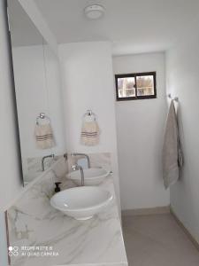 a white bathroom with two sinks and a mirror at Casa Suite Palmar del viento FRENTE, FRENTE AL MAR in Moñitos