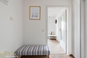 a white hallway with a striped bench in a room at Pineapple Apartments Dresden Mitte II - free parking in Dresden