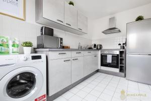 a kitchen with a washing machine and a refrigerator at Pineapple Apartments Dresden Mitte II - free parking in Dresden