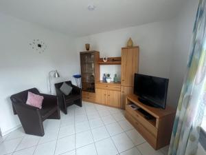 ein Wohnzimmer mit einem TV und einem Stuhl in der Unterkunft Holiday Home Reissmann by Interhome in Norden