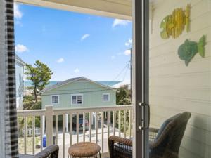 a screened in porch with a view of a house at Breezy Does It - Take it "br-eezy" while you stay in the heart of Carolina Beach, One minute walk to the beach! condo in Carolina Beach