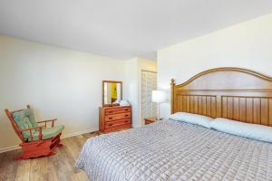 a bedroom with a bed and a chair and a mirror at Windy Dunes 138 in Avon