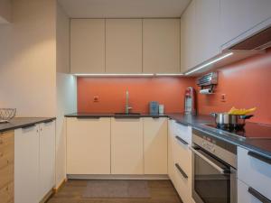 オヴロナにあるApartment Plein Soleil A 9 by Interhomeの白いキャビネットとオレンジ色の壁が備わるキッチン
