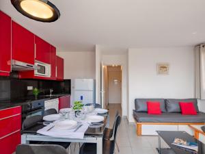 a kitchen with red cabinets and a table with plates on it at Apartment Les Coteaux de la Nartelle-17 by Interhome in Sainte-Maxime