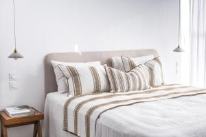 um quarto branco com uma cama com almofadas listradas em Suites 23 em Cassis