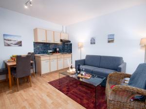 ein Wohnzimmer mit einem Sofa und einem Tisch sowie eine Küche in der Unterkunft Apartment Düne by Interhome in Norddeich