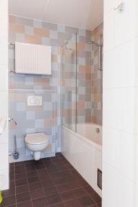 a bathroom with a toilet and a tub and a sink at Holiday Home Bungalowpark It Wiid by Interhome in Eernewoude +18 photos