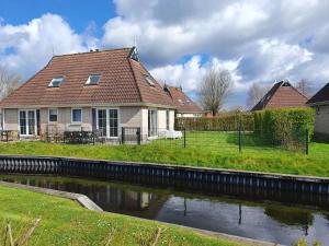 a house with a river in front of it at Holiday Home Bungalowpark It Wiid by Interhome in Eernewoude