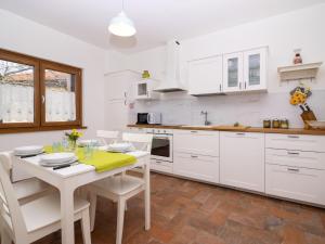 a kitchen with white cabinets and a table and chairs at Holiday Home Casa di Nonno by Interhome in Cividale del Friuli