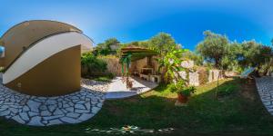 uitzicht op een tuin met een gebouw en een terras bij Sofia and Soul Studios in Kalamitsi