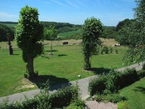 a green field with trees and cows in the distance at Holiday Home Bungalowpark Landsrade by Interhome in Gulpen