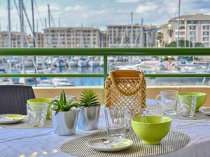 una mesa con platos y vasos en un balcón con puerto en Apartment Bleu Marine-5 by Interhome, en Fréjus