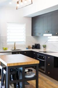 a kitchen with black cabinets and a wooden table at Industrial Luxe Villa - Boutique 1 bedroom luxury Villa in Edge Hill