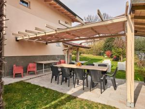 een patio met een houten tafel en stoelen onder een pergola bij Villa Giuseppina by Interhome in Besozzo