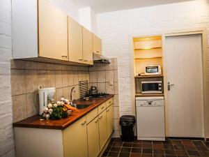 een keuken met witte kasten en een aanrecht met bloemen erop bij Holiday Home Bungalowpark Landsrade by Interhome in Gulpen