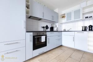 Pineapple Apartments Dresden Zwinger V - 78 qm - 1x free parking في درسدن: مطبخ أبيض مع خزائن بيضاء وأجهزة