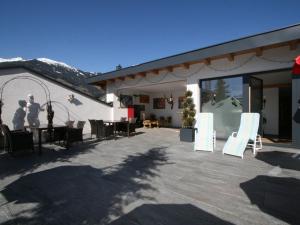 a patio with white chairs and tables and a building at Apartment Erzherzog's Apts-Zillertal Kaiser Lodge by Interhome in Uderns