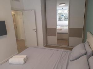 a bedroom with a white bed and a large mirror at Hakerem apartment in Tel Aviv