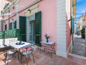 een patio met 2 tafels en stoelen in een roze gebouw bij Apartment Ponente N-2 by Interhome in San Vincenzo