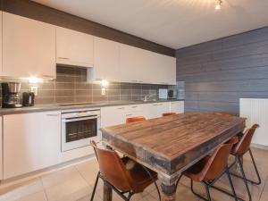 a kitchen with a wooden table and chairs at Apartment The Horseshoe with parking by Interhome in Bredene
