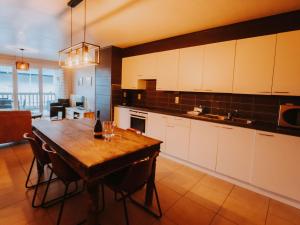 uma cozinha com uma mesa de madeira e armários brancos em Apartment De Paddock-1 by Interhome em Bredene