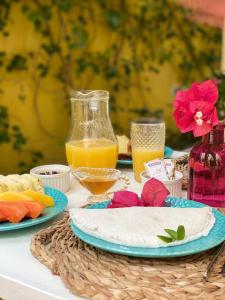 a table topped with plates of food and orange juice at Zion Suítes in Jericoacoara