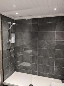 uma casa de banho com um chuveiro com azulejos pretos em sorn inn holiday apartments em Sorn