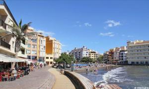 a beach with buildings and people sitting on a sidewalk at Spacious Chalet Next to the Sea - Airport in San Isidro