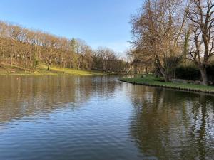 a body of water with trees and a park at L'Eden in Saint-Rémy-lès-Chevreuse