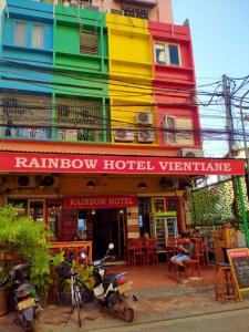 um edifício colorido com um homem sentado à frente dele em Rainbow Hotel Vientiane em Vientiane