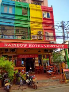 a colorful building with a man sitting in front of it at Rainbow Hotel Vientiane in Vientiane