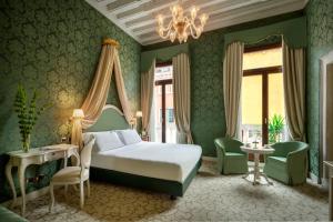 zieloną sypialnię z łóżkiem i żyrandolem w obiekcie Maison Venezia | UNA Esperienze w Wenecji
