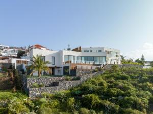 a house on a hill with a stone wall at Serenity Villa on the Cliff with climatized pool in Sauzal