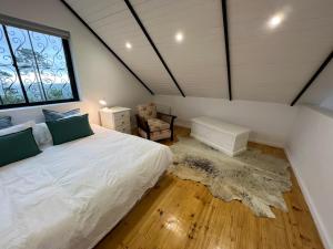 - une chambre avec un lit blanc et une fenêtre dans l'établissement Featherstone View Cottage, à Grahamstown