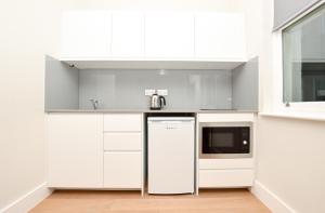 a kitchen with white cabinets and a dishwasher at Fitzroy Serviced Apartments by Concept Apartments in London