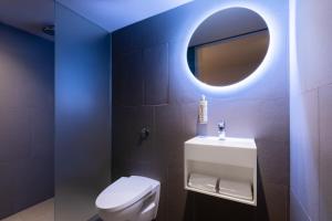 La salle de bains est pourvue de toilettes blanches et d'un miroir. dans l'établissement Zedwell Underground Hotel Tottenham Court Rd, à Londres