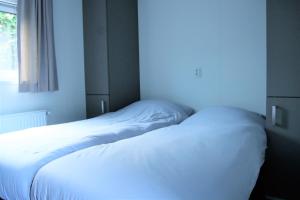 - un lit blanc dans une chambre avec fenêtre dans l'établissement Chalet Merel, à Drijber
