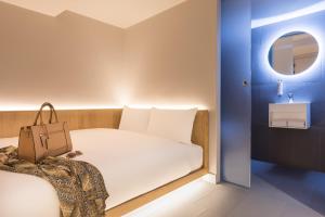 Un pequeño dormitorio con una cama blanca y un lavabo en Zedwell Underground Hotel Tottenham Court Rd, en Londres