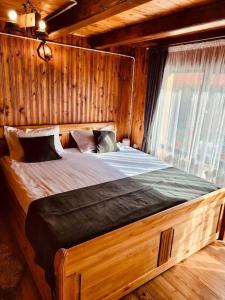 a bedroom with a large bed in a wooden room at River House Transylvania in Frăsinet