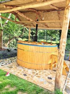 Un bain à remous en bois est installé sous une structure en bois. dans l'établissement River House Transylvania, à Frăsinet