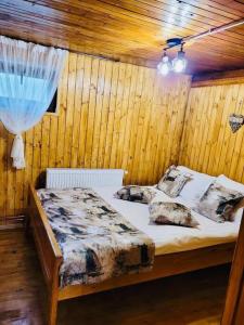 a bedroom with a bed in a wooden wall at River House Transylvania in Frăsinet